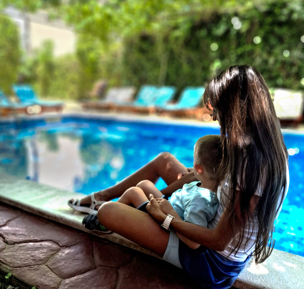 mom and son sitting by the pool