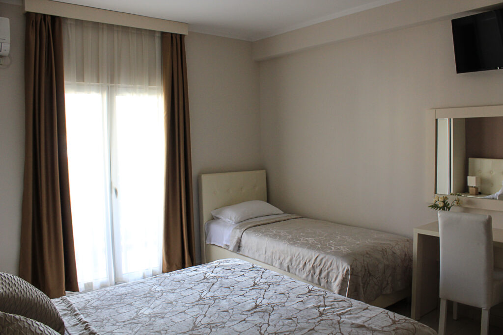 a single bed in hotel room next to the king size bed