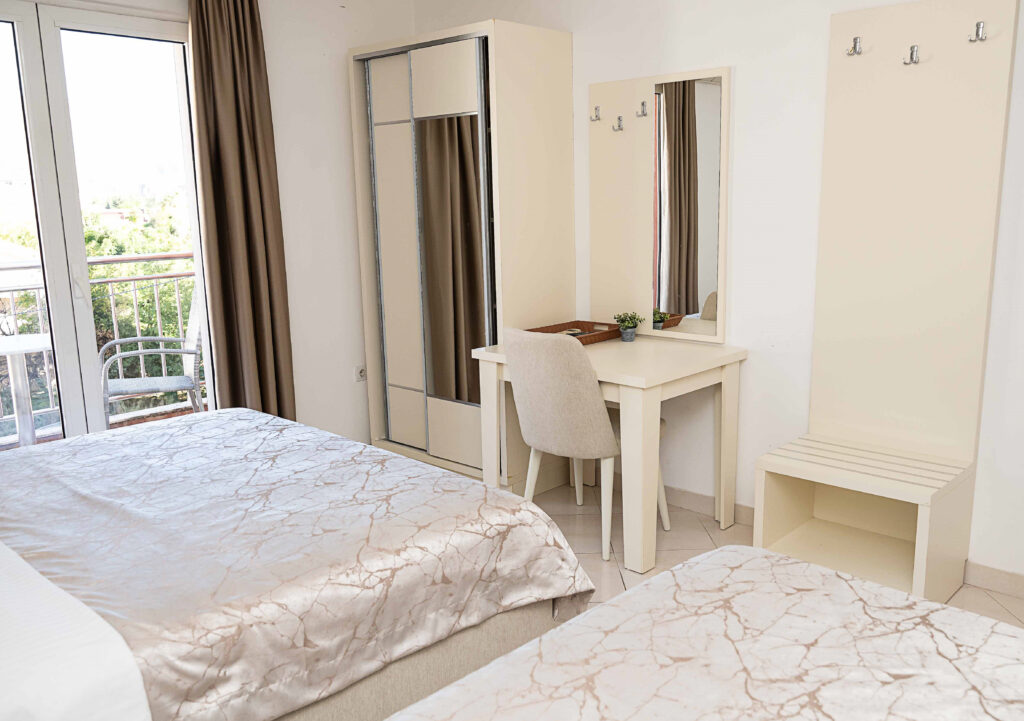 desk in a hotel room with balcony and bed